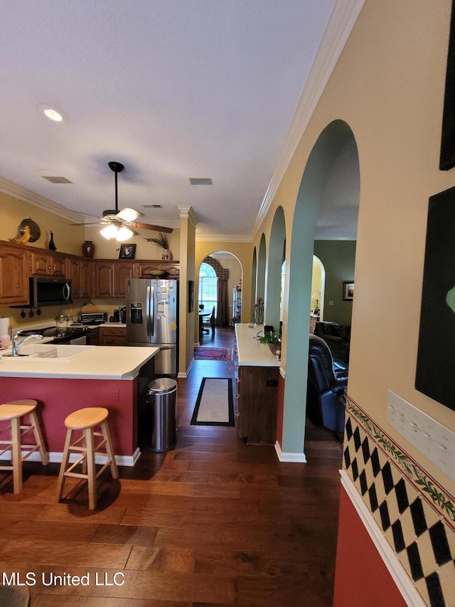 8475 Windersgate Dr, Olive Branch, MS 38654 - kitchen featuring appliances with stainless steel finishes, ornamental molding, dark wood-style floors, arched walkways, and ceiling fan