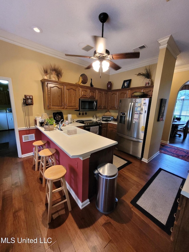 8475 Windersgate Dr, Olive Branch, MS 38654 - kitchen with appliances with stainless steel finishes, a peninsula, ornamental molding, a breakfast bar area, and light countertops