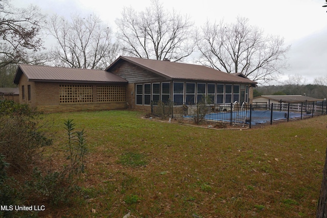 rear view of house with a lawn, a sunroom, and a covered pool