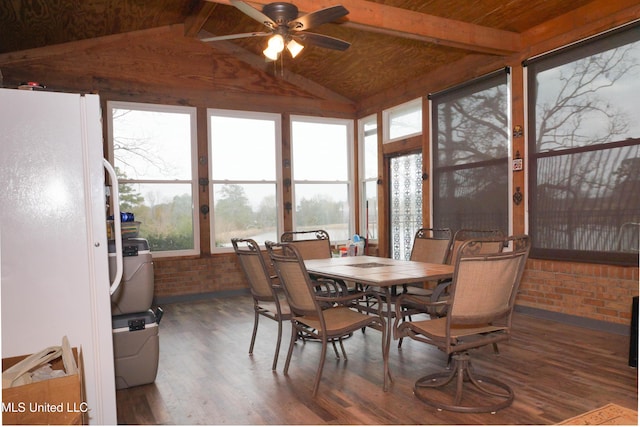 dining space featuring lofted ceiling with beams, dark hardwood / wood-style floors, ceiling fan, and brick wall