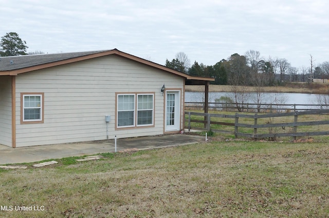 view of side of home featuring a yard, a water view, and a patio