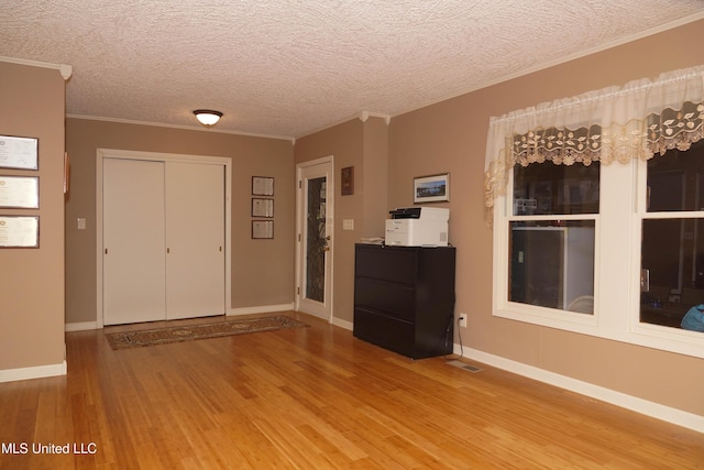 entryway with hardwood / wood-style floors, a textured ceiling, and crown molding