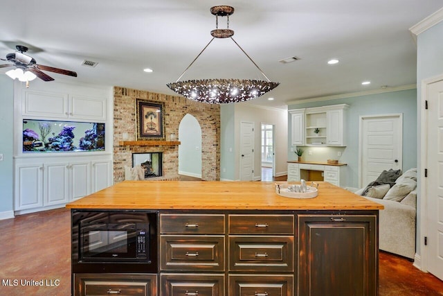 kitchen with crown molding, dark brown cabinetry, black microwave, and wooden counters