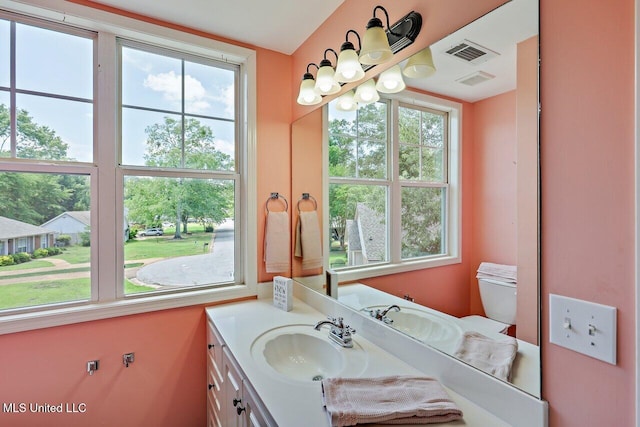 half bath featuring vanity, toilet, and visible vents