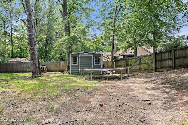 view of yard featuring a fenced backyard, a trampoline, an outdoor structure, and a shed