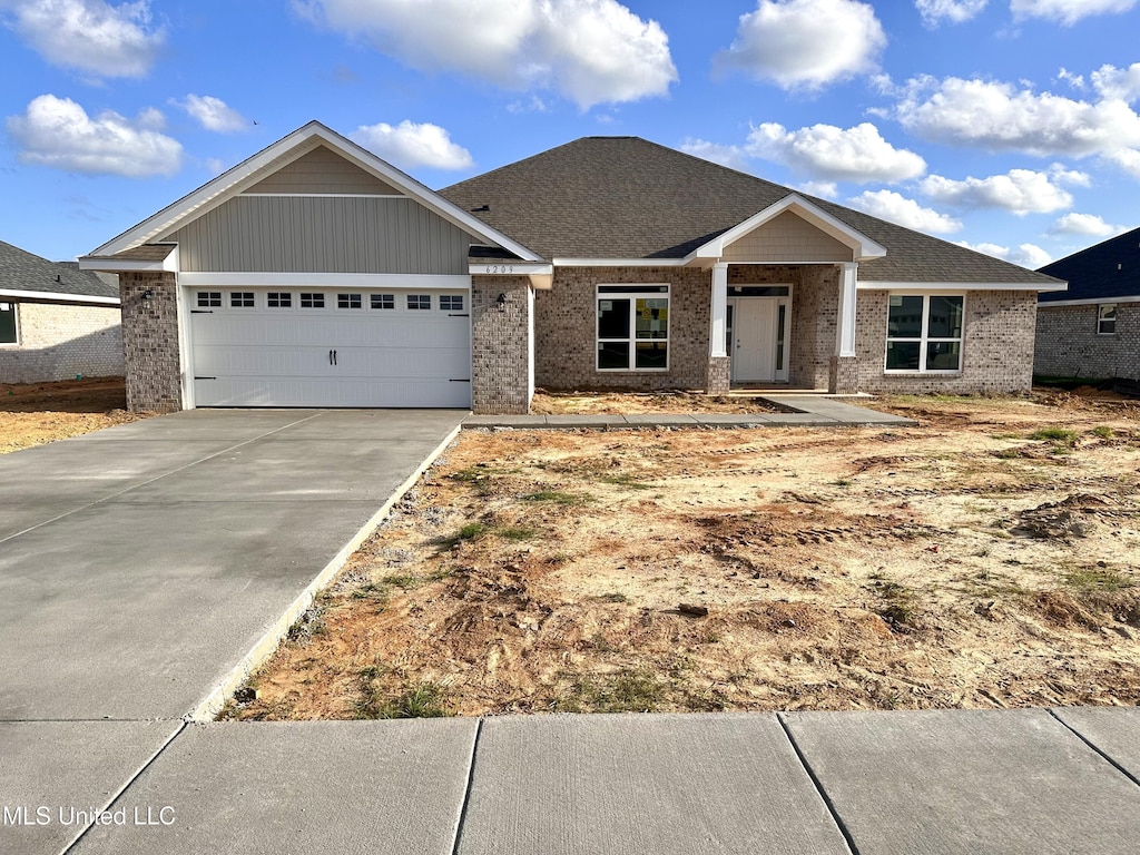 craftsman inspired home with driveway, an attached garage, and brick siding