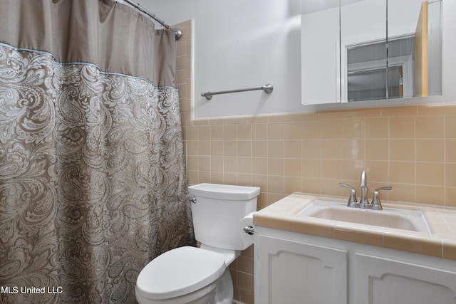 bathroom featuring a wainscoted wall, tile walls, toilet, and vanity