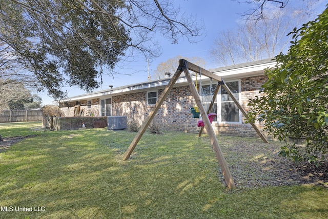 back of property with cooling unit, brick siding, a yard, and fence