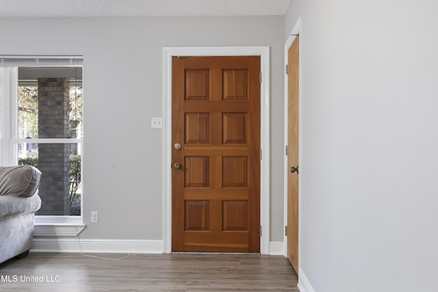 foyer featuring baseboards and wood finished floors