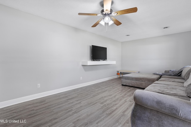 living area featuring a ceiling fan, baseboards, and wood finished floors