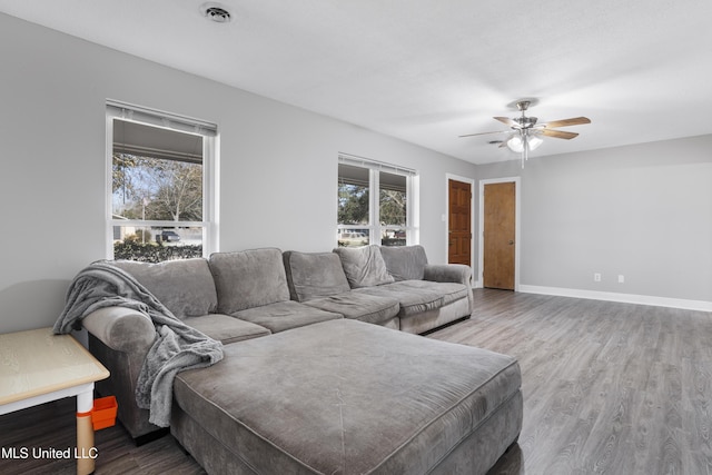 living area featuring a wealth of natural light, visible vents, baseboards, and wood finished floors