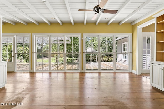 unfurnished sunroom featuring beamed ceiling, a healthy amount of sunlight, and ceiling fan