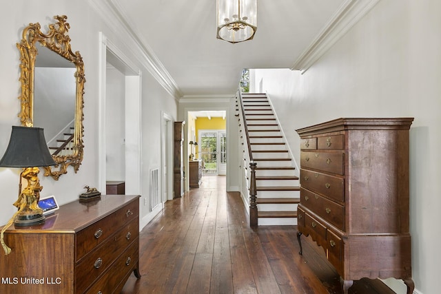 entrance foyer with ornamental molding, a notable chandelier, and dark hardwood / wood-style flooring