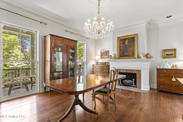 dining room featuring a brick fireplace, ornamental molding, dark hardwood / wood-style floors, and a chandelier