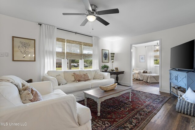 living area with ceiling fan, plenty of natural light, baseboards, and dark wood-type flooring