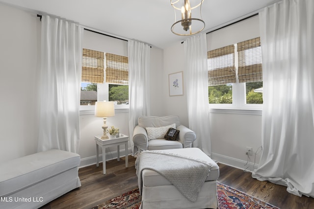 living area featuring baseboards, wood finished floors, and a chandelier
