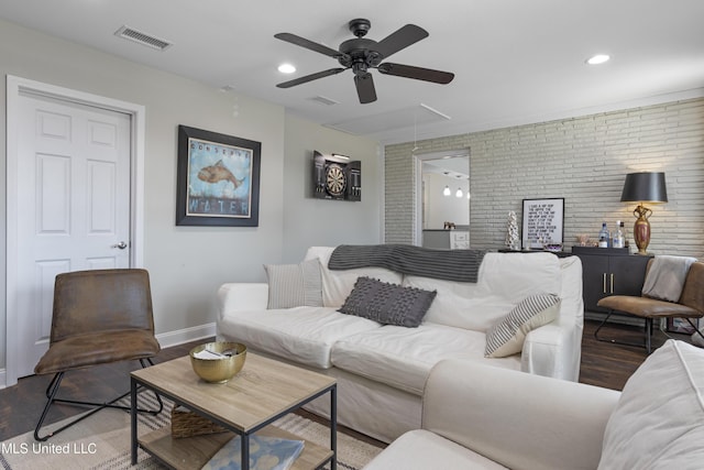 living area with ceiling fan, attic access, brick wall, visible vents, and wood finished floors