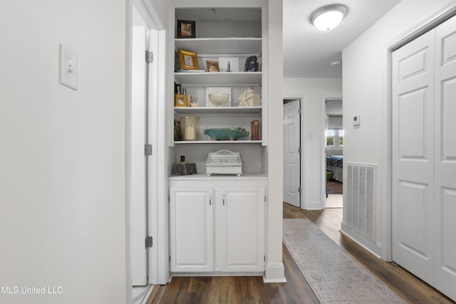 hall featuring dark wood-type flooring and visible vents
