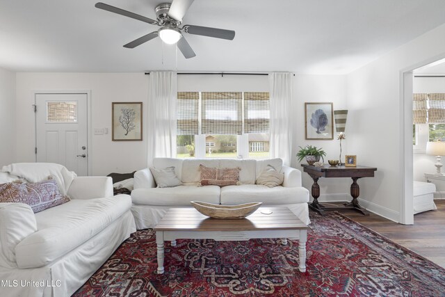 living area with baseboards, a ceiling fan, and wood finished floors