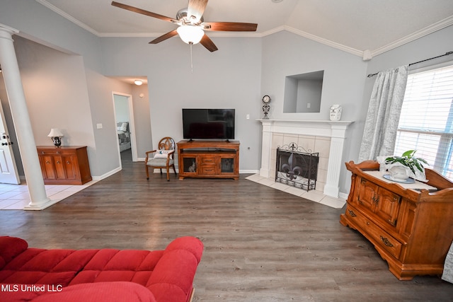 living room featuring a tiled fireplace, ceiling fan, vaulted ceiling, dark hardwood / wood-style floors, and crown molding