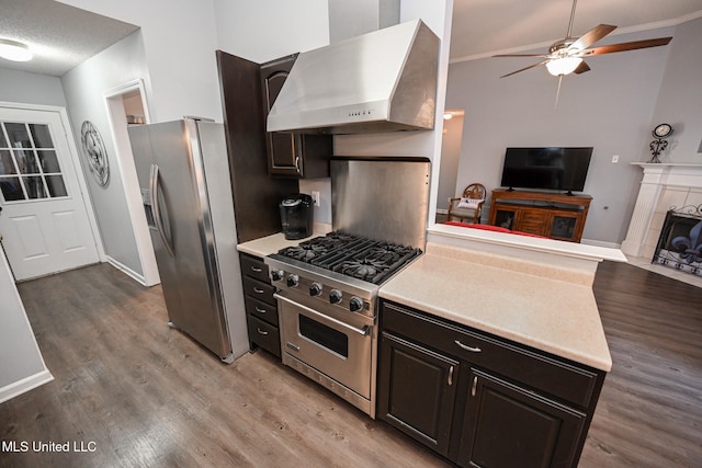 kitchen featuring light hardwood / wood-style flooring, wall chimney range hood, stainless steel appliances, and a tile fireplace