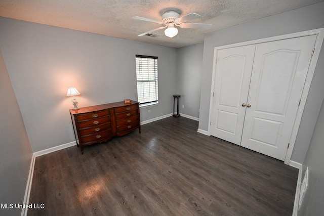 unfurnished bedroom with a closet, dark hardwood / wood-style floors, a textured ceiling, and ceiling fan