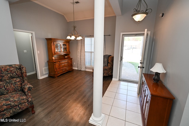 entryway with ornate columns, light hardwood / wood-style floors, lofted ceiling, a notable chandelier, and ornamental molding