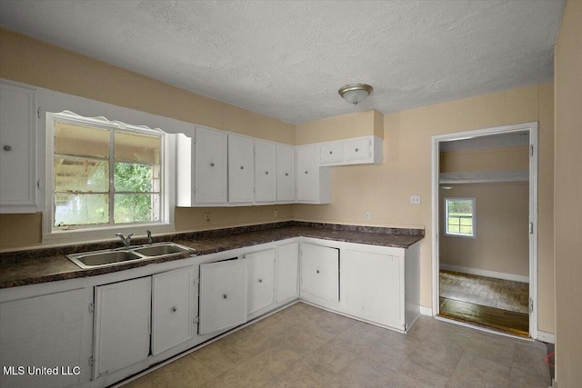 2862 Oak Forest Dr, Jackson, MS 39212 - kitchen featuring a sink, white cabinetry, dark countertops, a textured ceiling, and baseboards