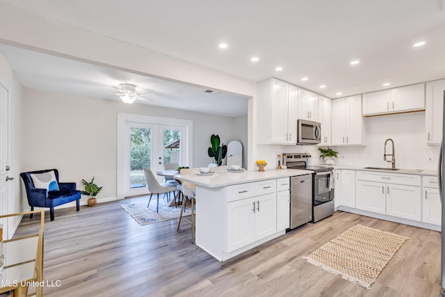 kitchen featuring kitchen peninsula, appliances with stainless steel finishes, sink, and white cabinetry