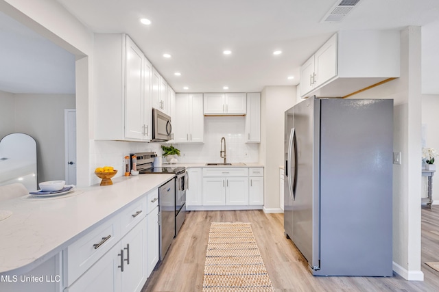 kitchen featuring light wood-type flooring, stainless steel appliances, white cabinetry, and sink