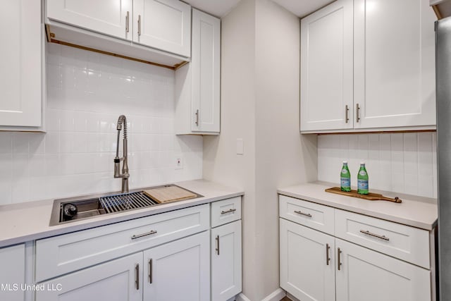 kitchen featuring tasteful backsplash, sink, and white cabinetry