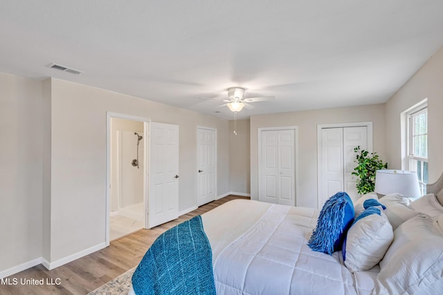 bedroom with ceiling fan, multiple closets, and light hardwood / wood-style floors