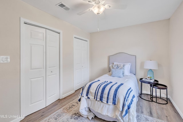 bedroom with ceiling fan, light hardwood / wood-style floors, and multiple closets