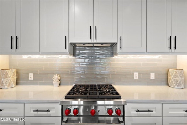 kitchen with white cabinets, backsplash, and high end stove