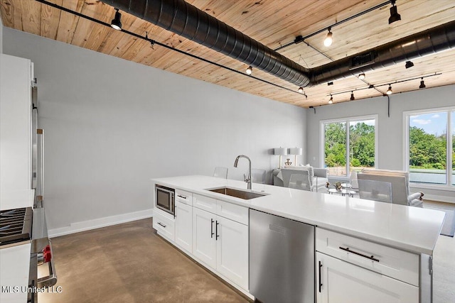 kitchen featuring appliances with stainless steel finishes, white cabinetry, sink, and concrete flooring