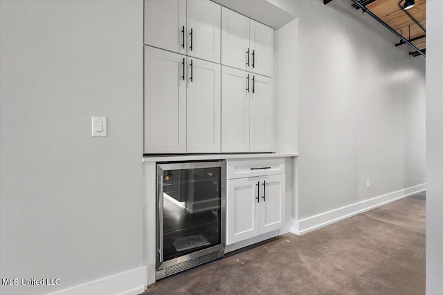 interior space featuring white cabinets, concrete flooring, and wine cooler