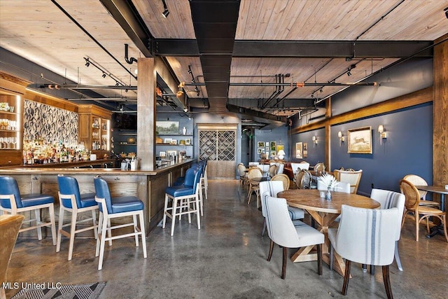 dining space featuring wood ceiling, beamed ceiling, and bar