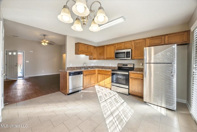 kitchen with ceiling fan with notable chandelier, stainless steel appliances, sink, hanging light fixtures, and light tile patterned floors