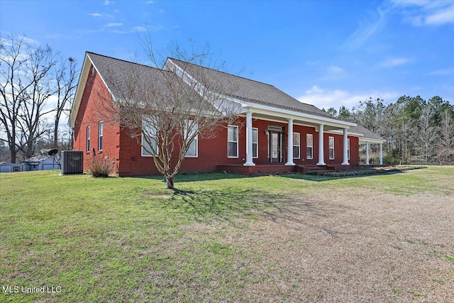 view of front of home featuring central air condition unit, covered porch, brick siding, roof with shingles, and a front yard