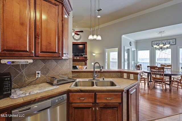 kitchen with backsplash, ornamental molding, a sink, dishwasher, and a peninsula