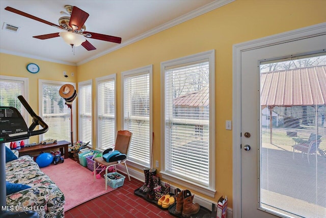 workout area featuring brick floor, visible vents, a ceiling fan, and ornamental molding