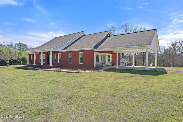 rear view of house featuring a patio, a yard, and a shingled roof