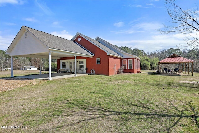 rear view of property with a yard, a shingled roof, brick siding, and a gazebo