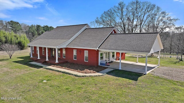 view of front of house featuring driveway, a shingled roof, a patio, a front yard, and brick siding