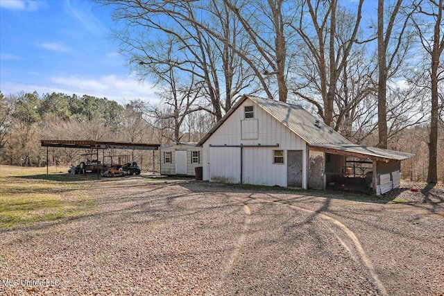 view of outbuilding featuring driveway, a carport, and an outbuilding