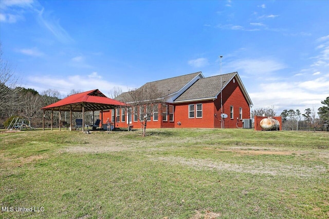 exterior space with cooling unit, brick siding, a yard, and a gazebo