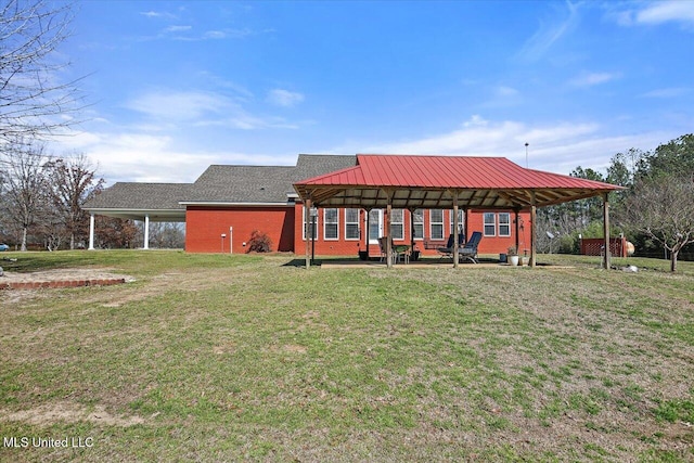 rear view of house with metal roof, a lawn, and brick siding