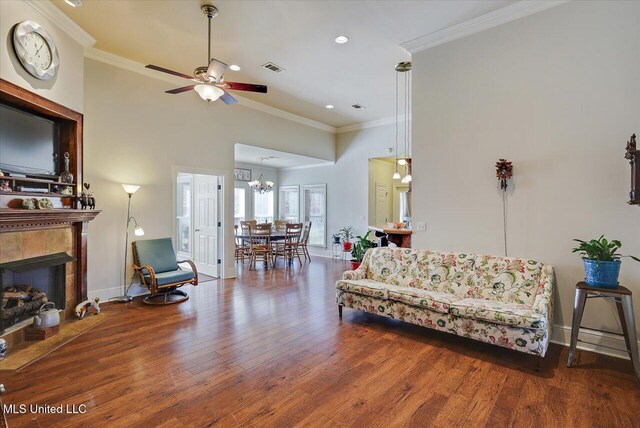 living room featuring a high ceiling, a fireplace, wood finished floors, and crown molding