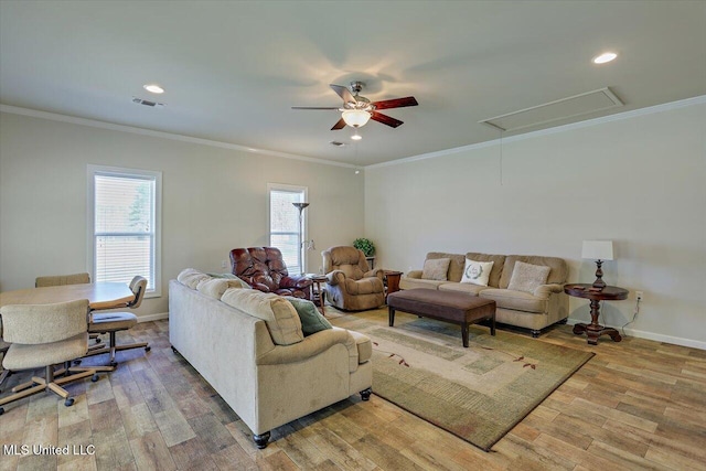 living room featuring light wood-type flooring, attic access, baseboards, and crown molding