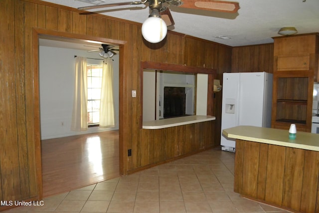 236 E Moon St, Ridgeland, MS 39157 - kitchen featuring white fridge with ice dispenser, a ceiling fan, brown cabinetry, wood walls, and light countertops